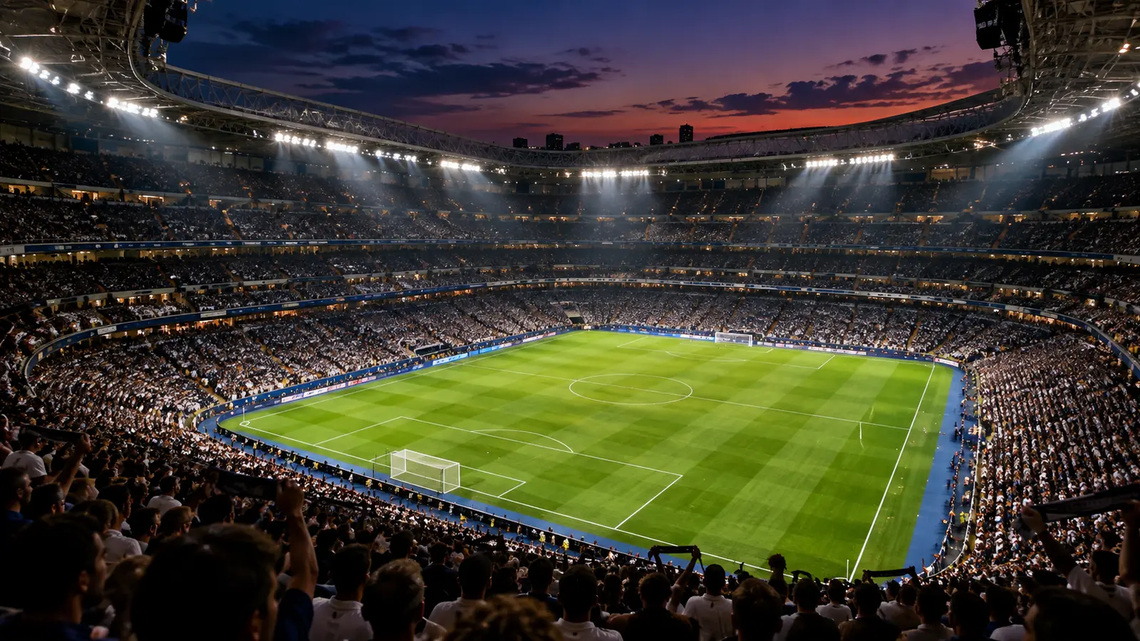Vista panorámica de un gran estadio de fútbol lleno de aficionados al anochecer, en alusión al ambiente de un Clásico.
