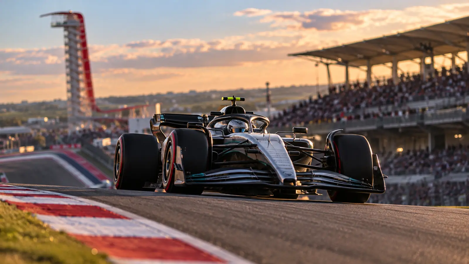Monoplaza plateado subiendo hacia la curva 1 en Texas Monoplaza de Fórmula 1 plateado y negro subiendo la cuesta de la curva 1 de un circuito texano al atardecer, con gradas llenas al fondo